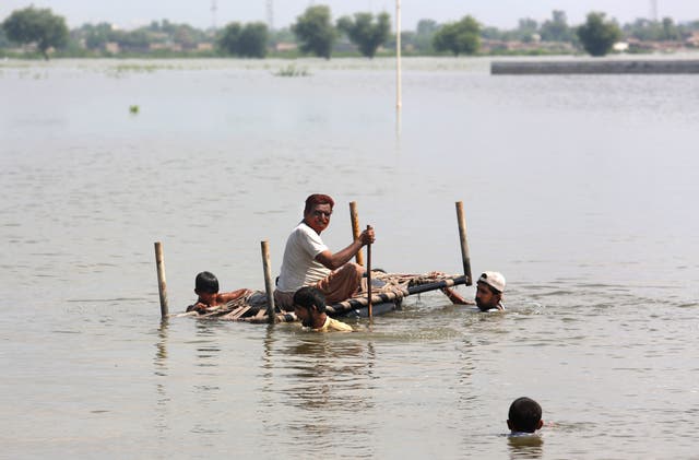 People try to salvage belongings from their nearby flooded home caused by heavy rain in Pakistan (Fareed Khan/AP)