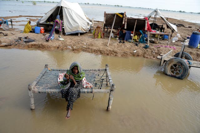 <p>A woman sits near her belongings surrounded by floodwaters, in Sohbat Pur city, a district of Pakistan's southwestern Baluchistan</p>
