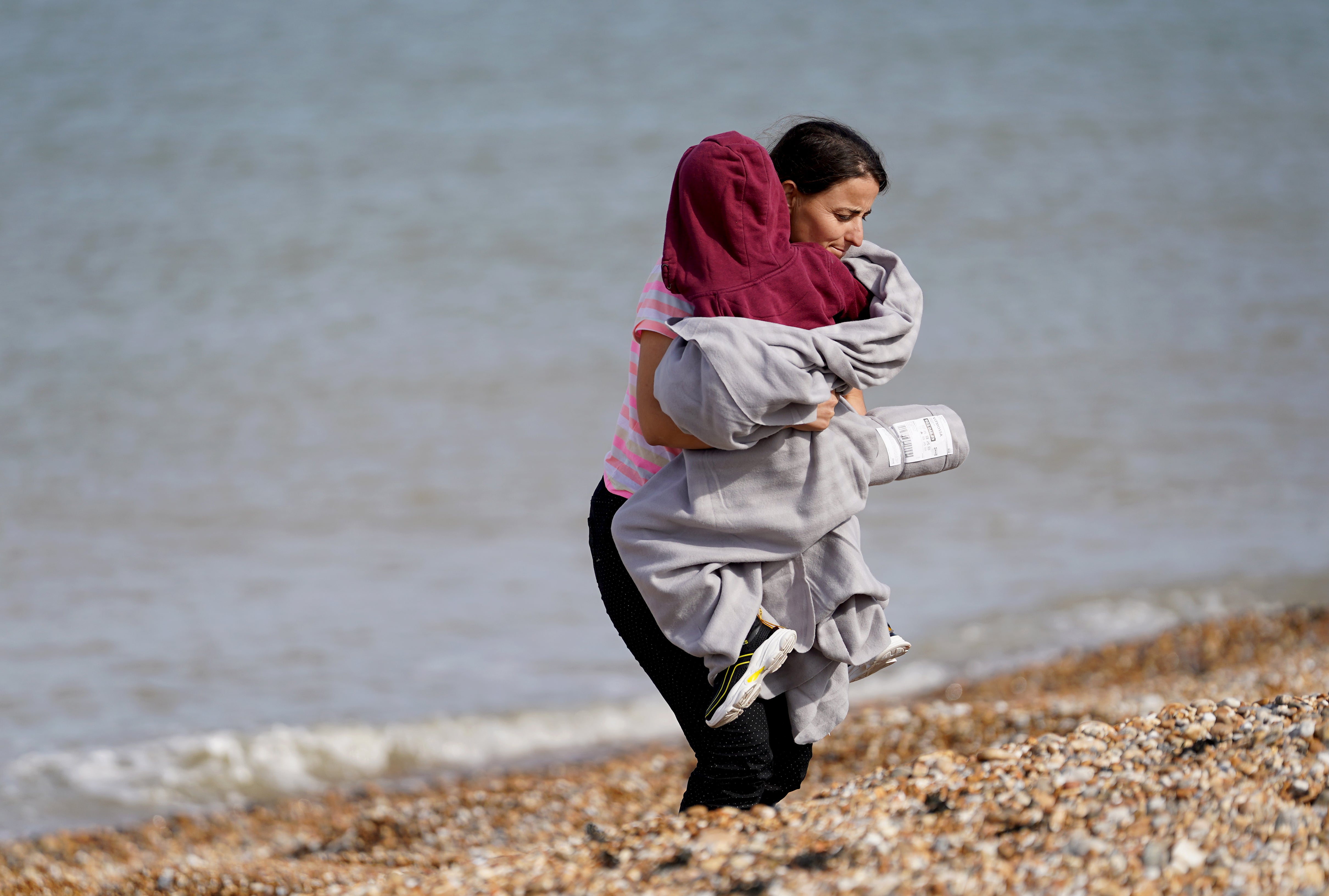 A woman and child thought to be migrants walk ashore in Dungeness, Kent (Gareth Fuller/PA)