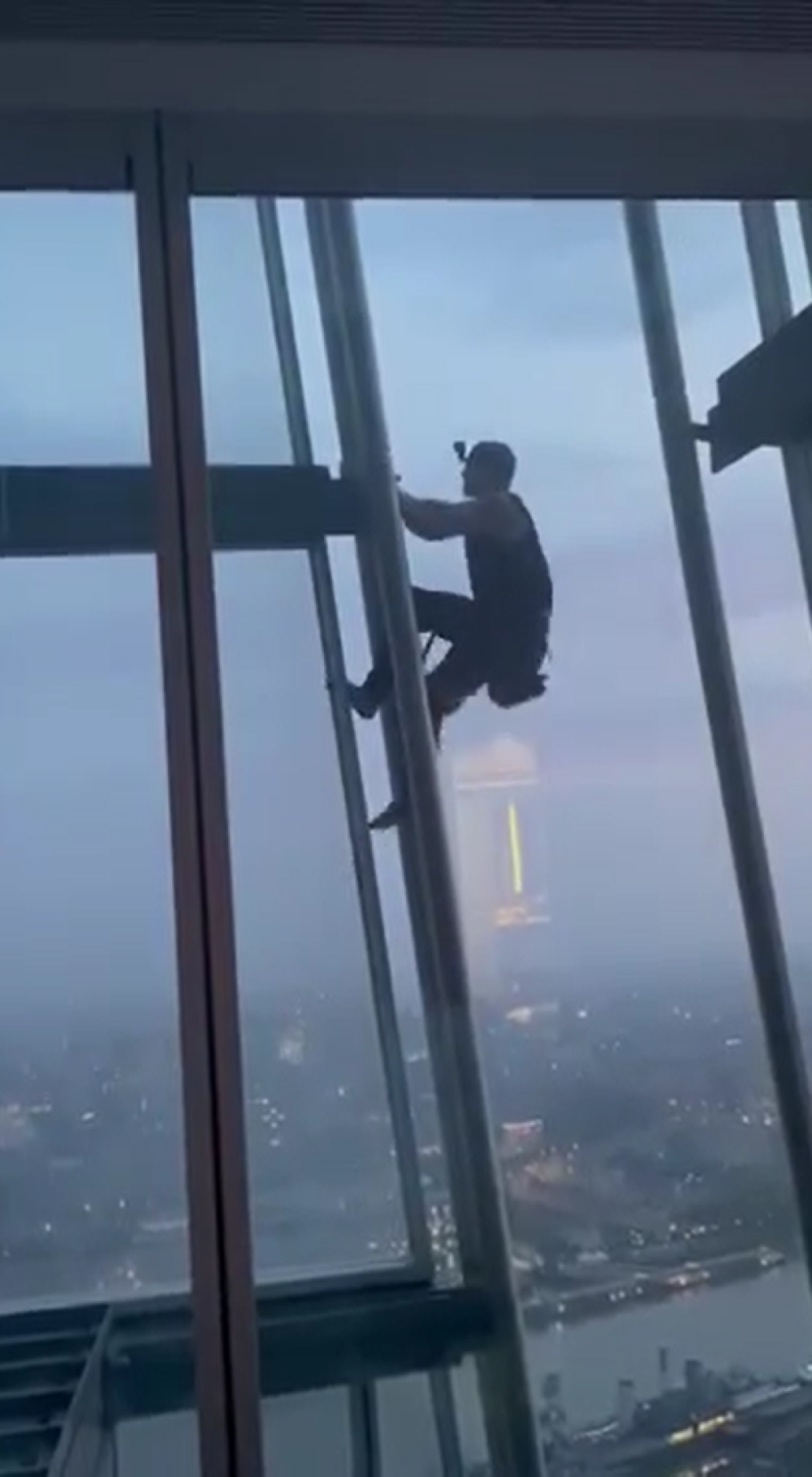 Couple wave at barefoot man climbing past their window at the Shard 40 floors up