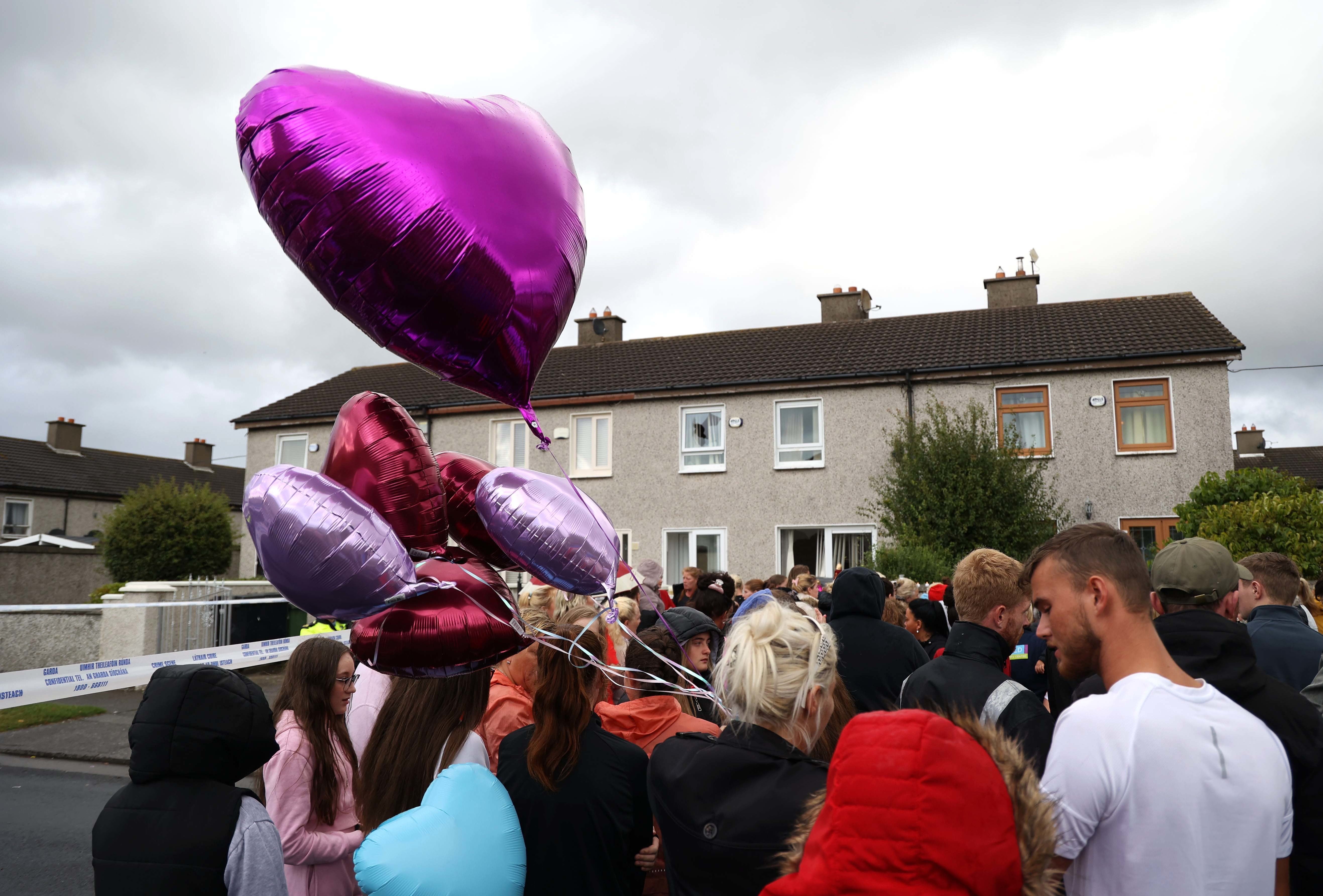 People attend a vigil outside a house on Rossfield Avenue in Tallaght, Dublin