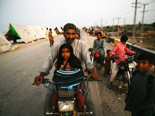 <p>Internally displaced flood-affected people gather outside their tents at a makeshift camp alongside flood waters after heavy monsoon rains in Sukkur, Sindh</p>