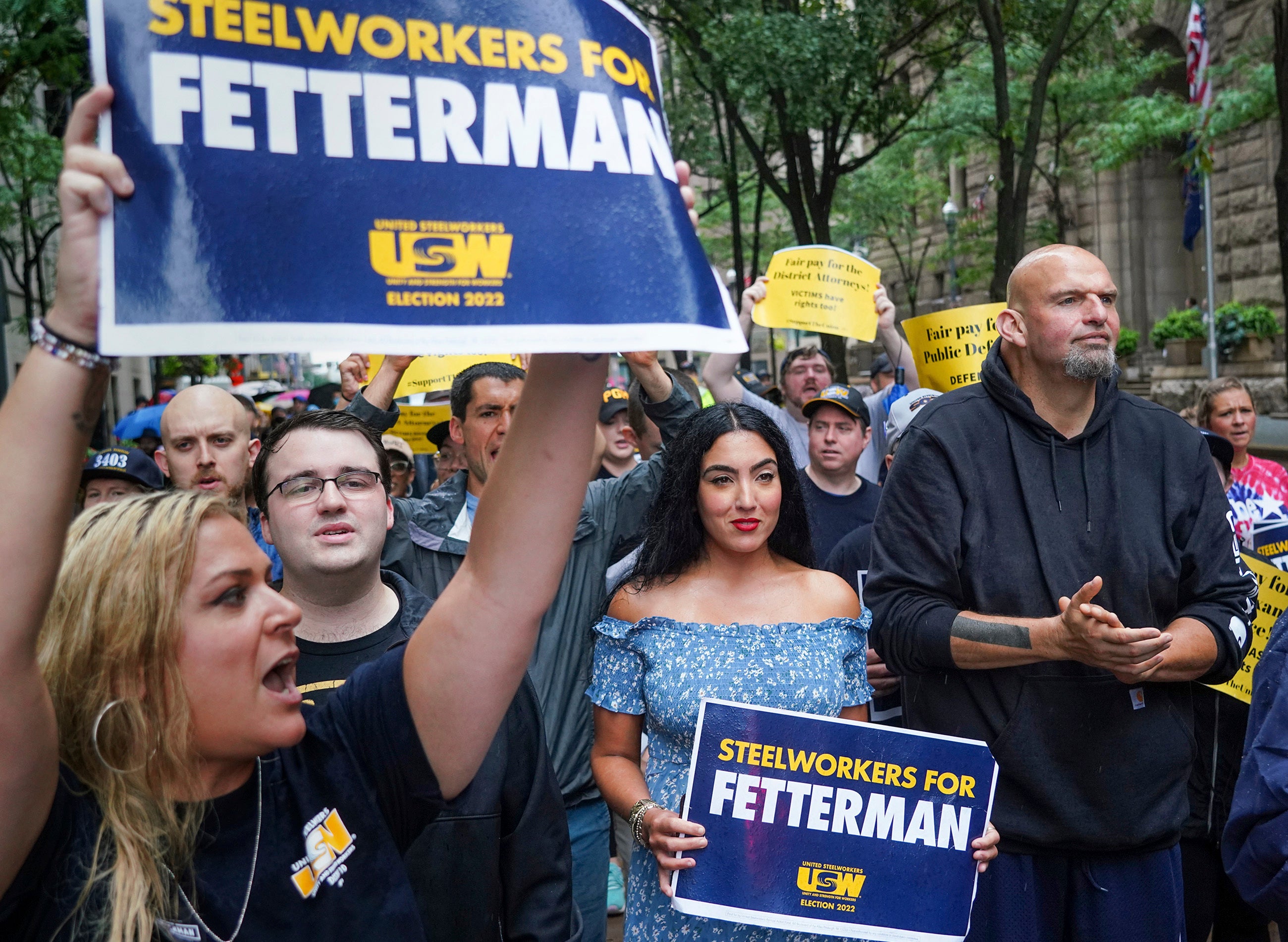 Supporters surround John Fetterman, right, Pennsylvania's Democratic lieutenant governor and senate candidate, during a Labor Day parade in downtown Pittsburgh, on Monday, Sept. 5, 2022. His wife, Gisele, in a blue dress holds a sign next to him.