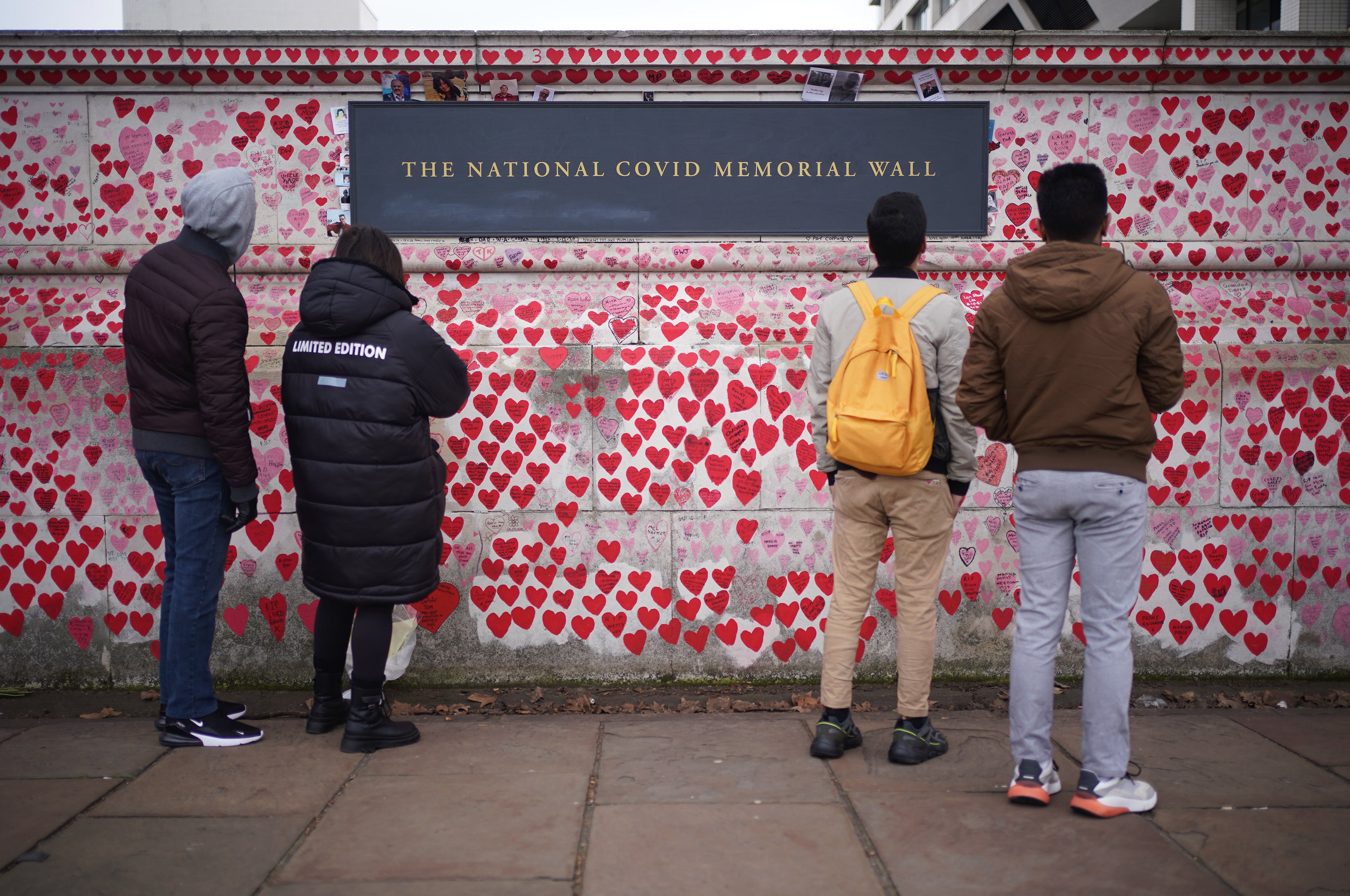 People look at tributes on the Covid memorial wall in central London (Yui Mok/PA)