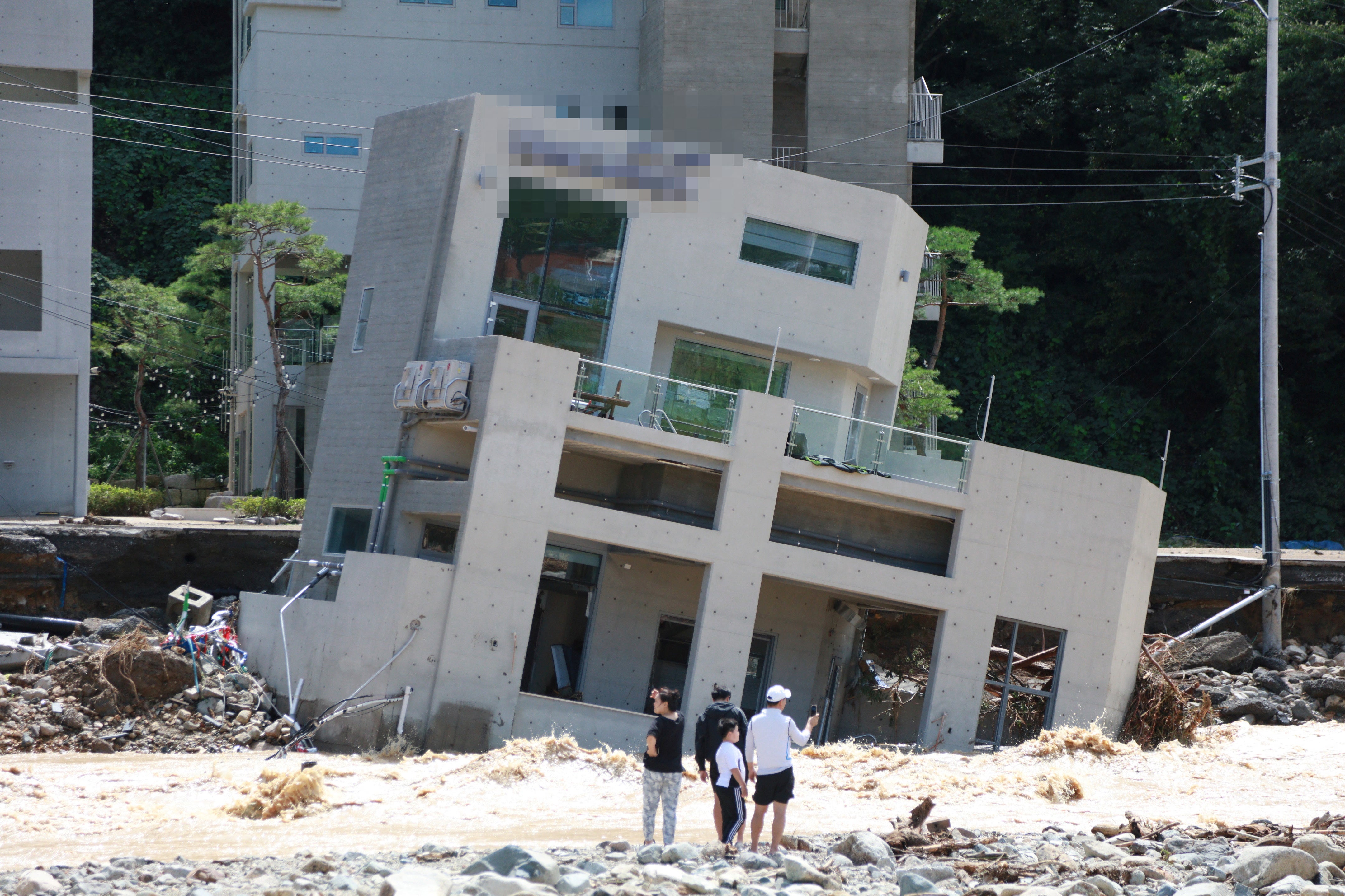 People stand in front of a collapsed building after Typhoon Hinnamnor made landfall in Pohang