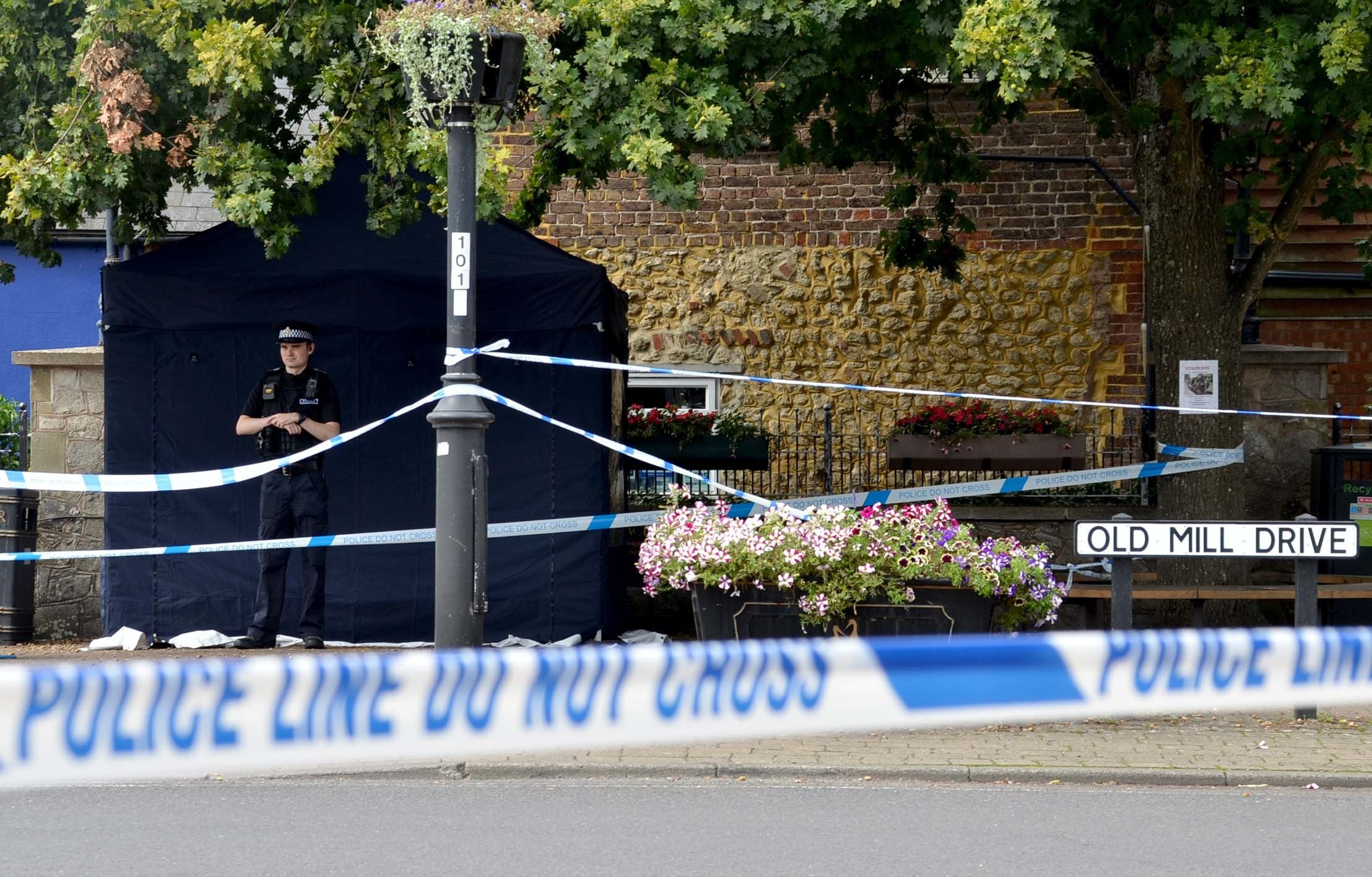 Police officers stand next to a police tent at the scene on at Place de Villerest on the junction of Old Mill Drive and the High Street in Storrington, West Sussex, after a man died. A 68-year-old man has been arrested on suspicion of murder police said. Picture date: Sunday September 4, 2022.