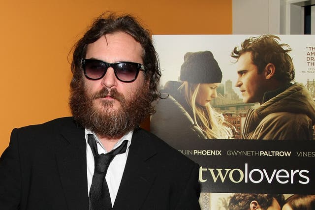 <p>Joaquin Phoenix poses dispassionately in front of a poster for his film ‘Two Lovers’ in 2009</p>