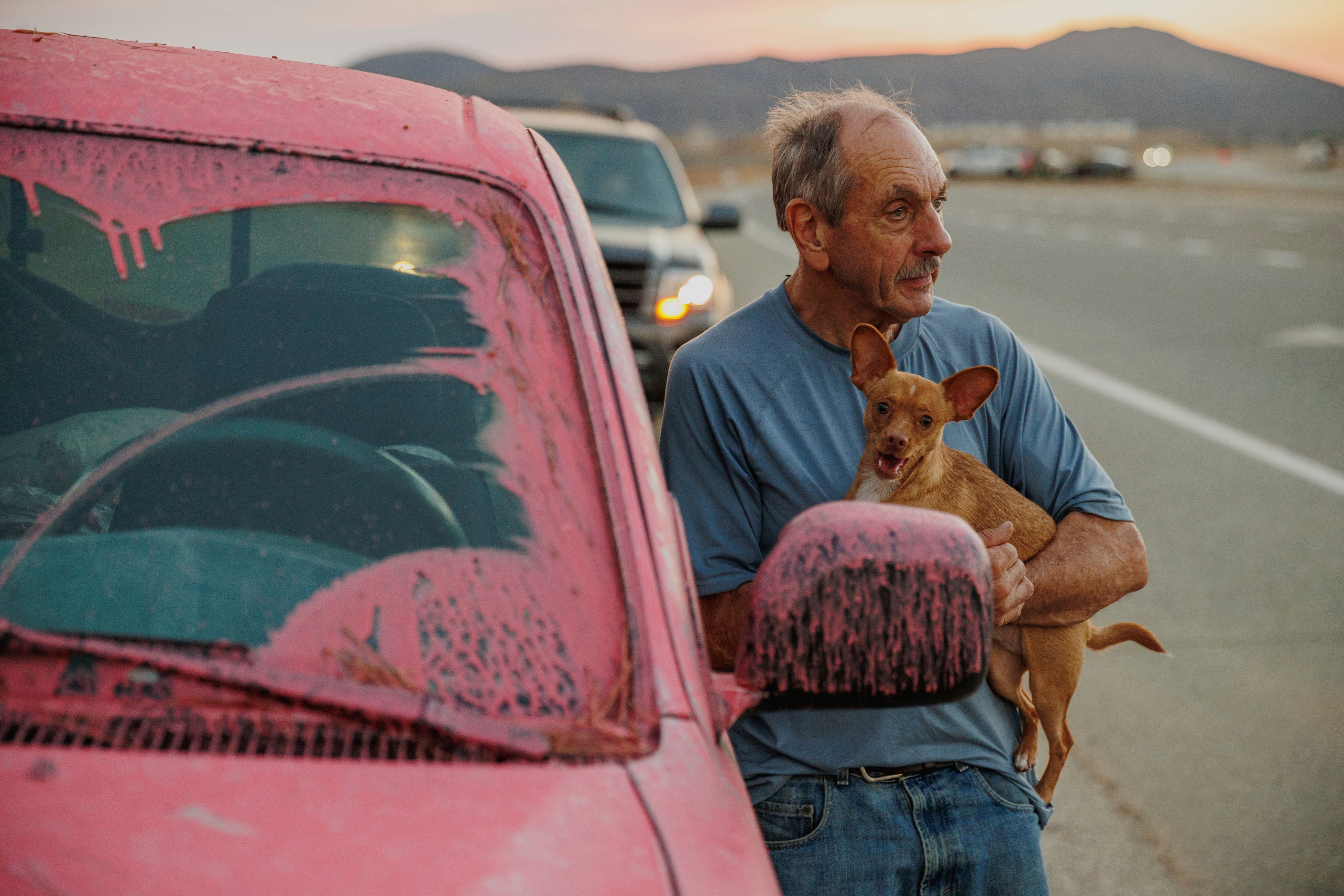 A man holds a dog after evacuating the Fairview Fire outside Hemet, California