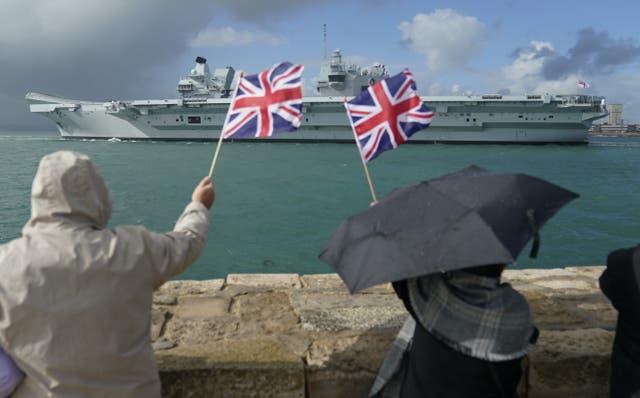 People wave from the shore as the Royal Navy aircraft carrier and flagship HMS Queen Elizabeth leaves Portsmouth Harbour for the United States, ahead of an autumn on operations and exercises in European waters. Picture date: Wednesday September 7, 2022. (Andrew Matthews/PA Wire)
