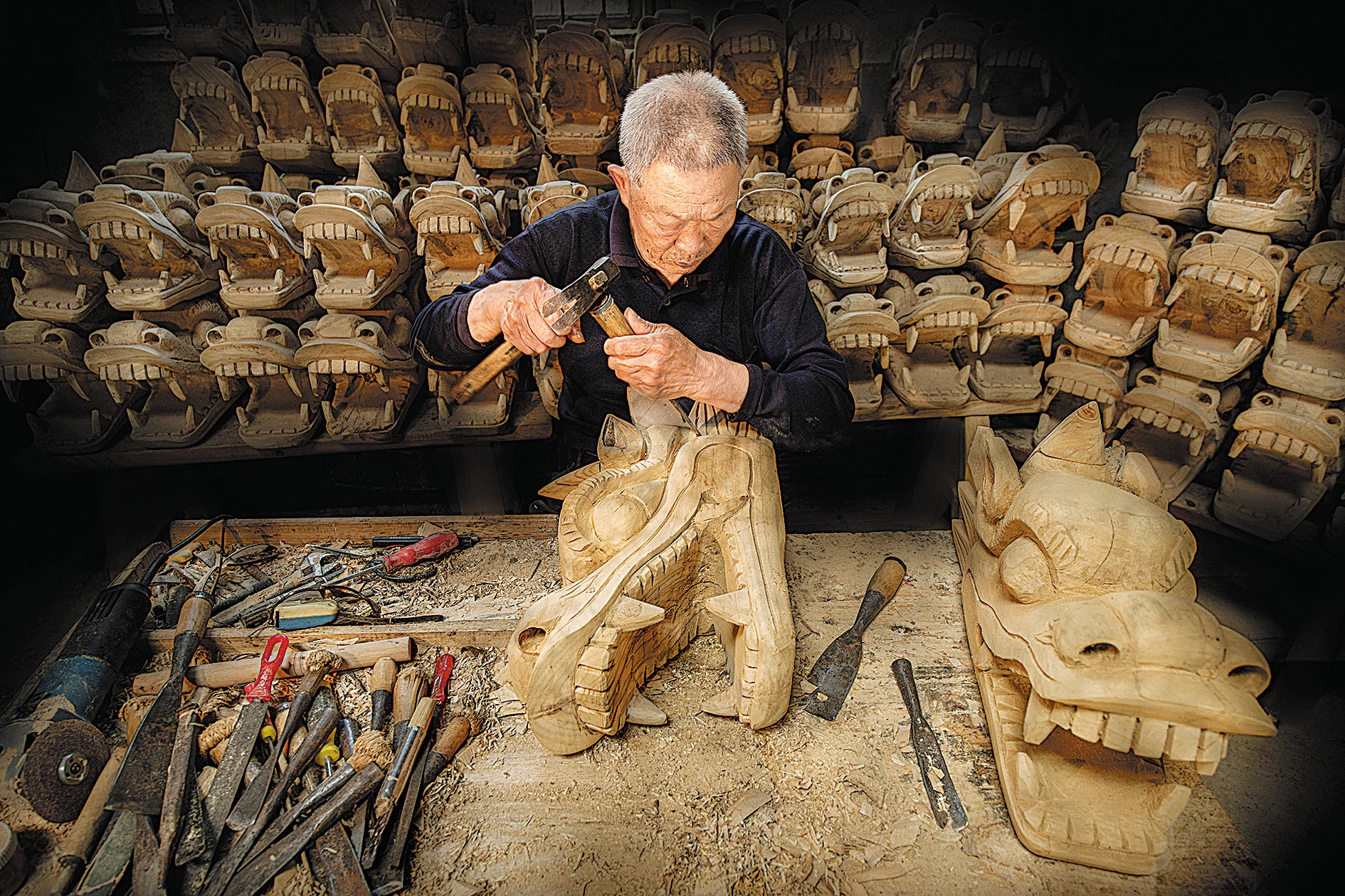 A wood-carver finishes details on the head of a dragon boat in Miluo in April