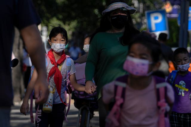 <p>Students wearing face masks are accompanied by their relatives as they head to a primary school in Beijing in September 2022 </p>