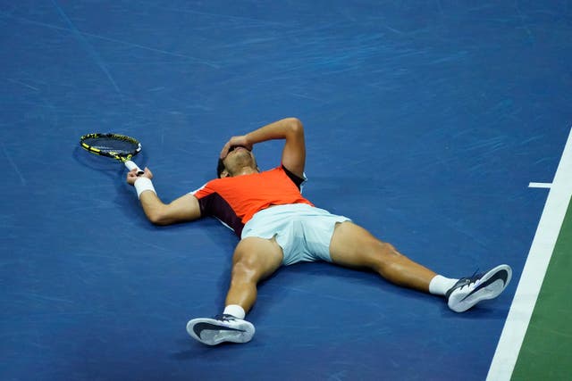 Carlos Alcaraz lies on the court after beating Jannik Sinner (Julia Nikhinson/AP)