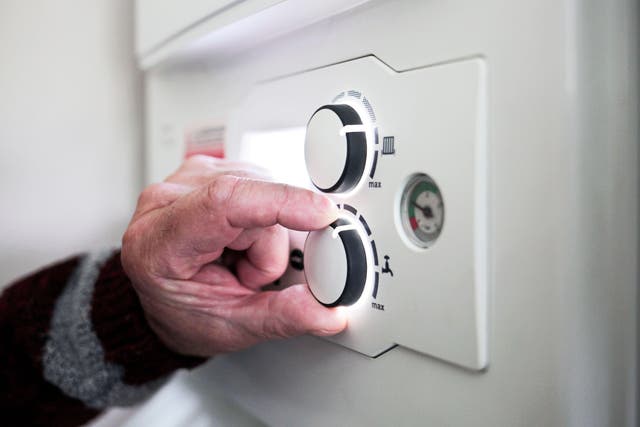 A pensioner adjusting the temperature control on his combi boiler (Stuart Boulton/Alamy/PA)