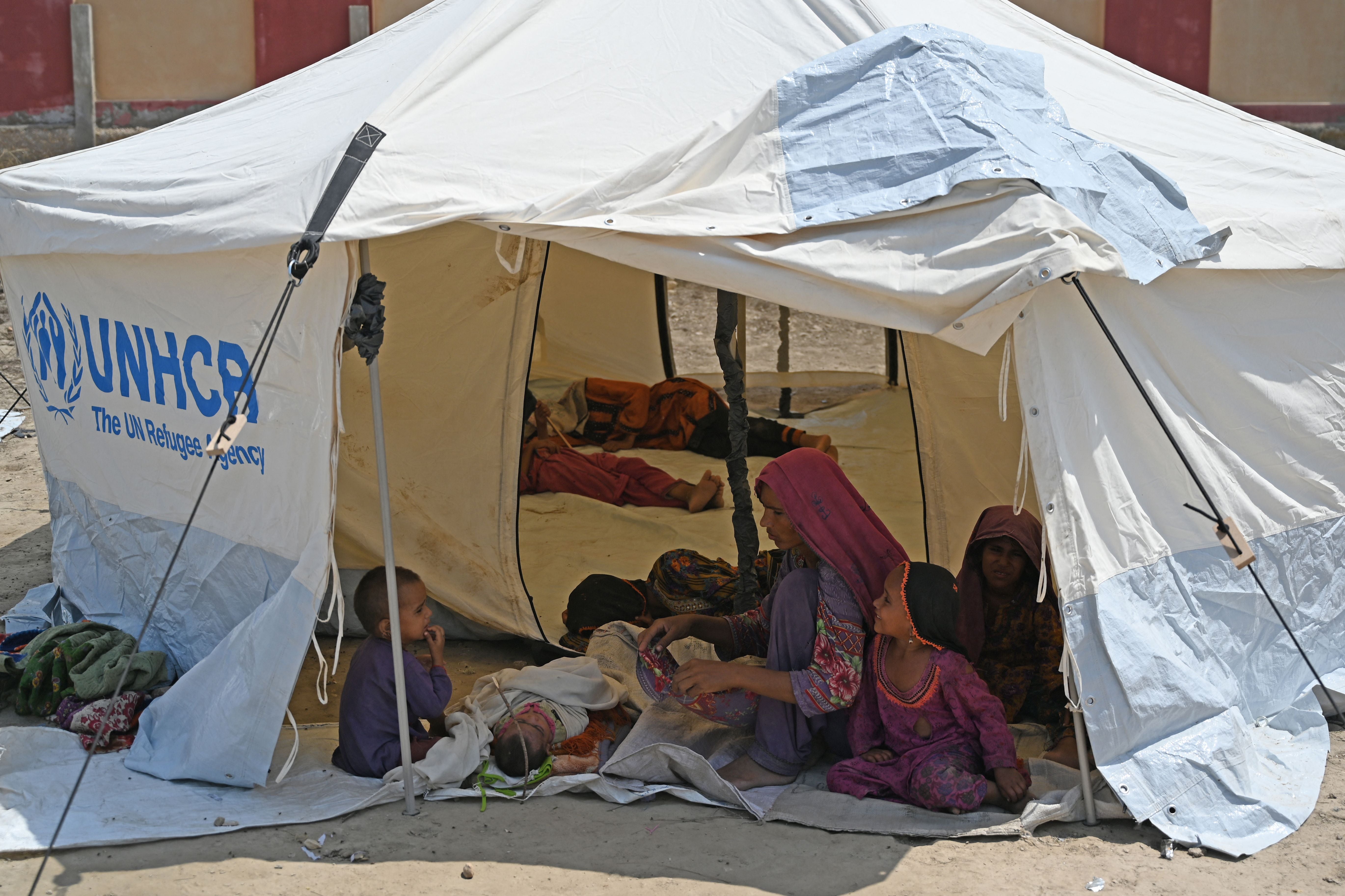 A woman sits beside her newborn baby in a United Nations High Commissioner for Refugees (UNHCR) tent at a makeshift camp in Sukkur, Sindh