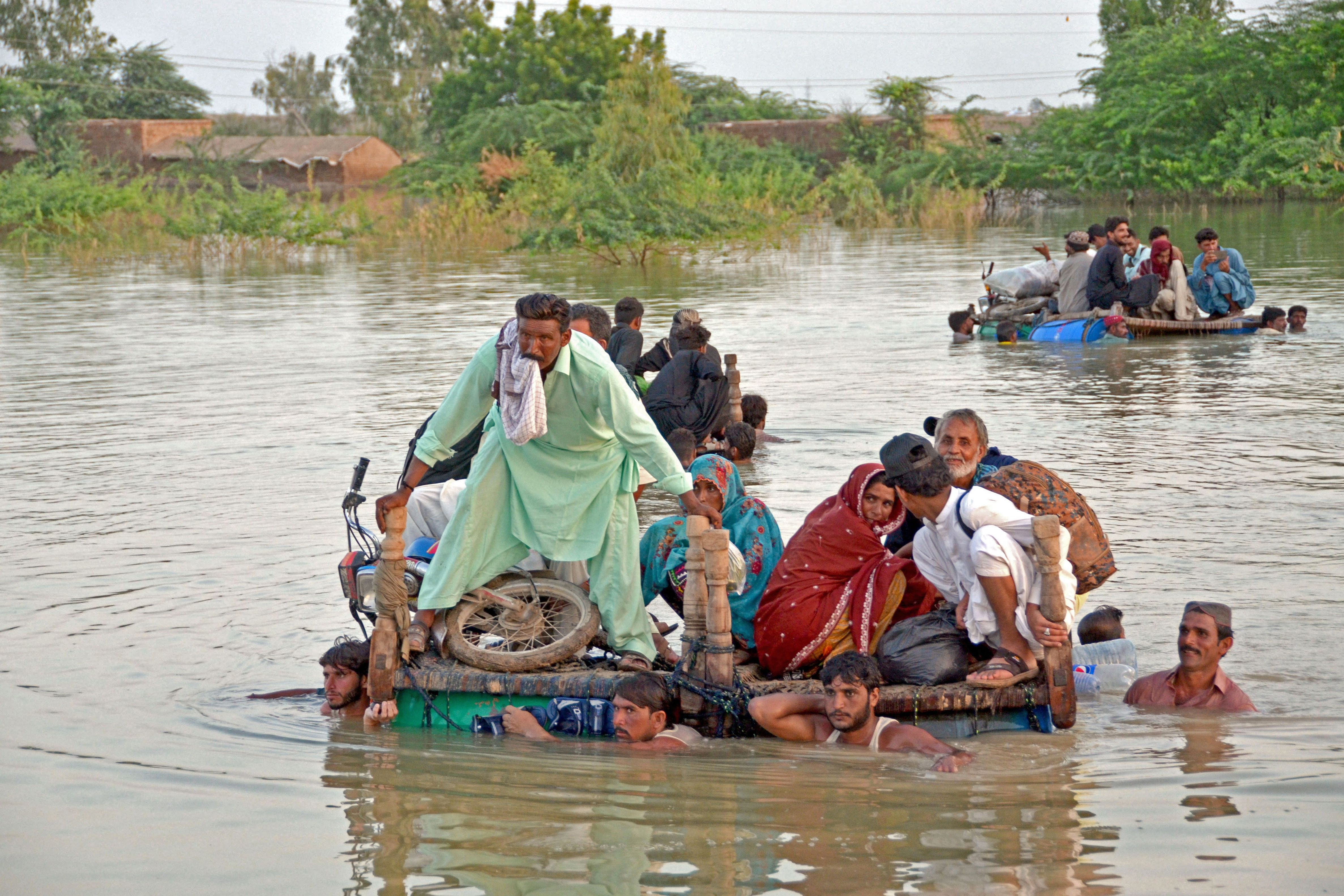 People wade through floodwaters in the Jaffarabad district of Balochistan province