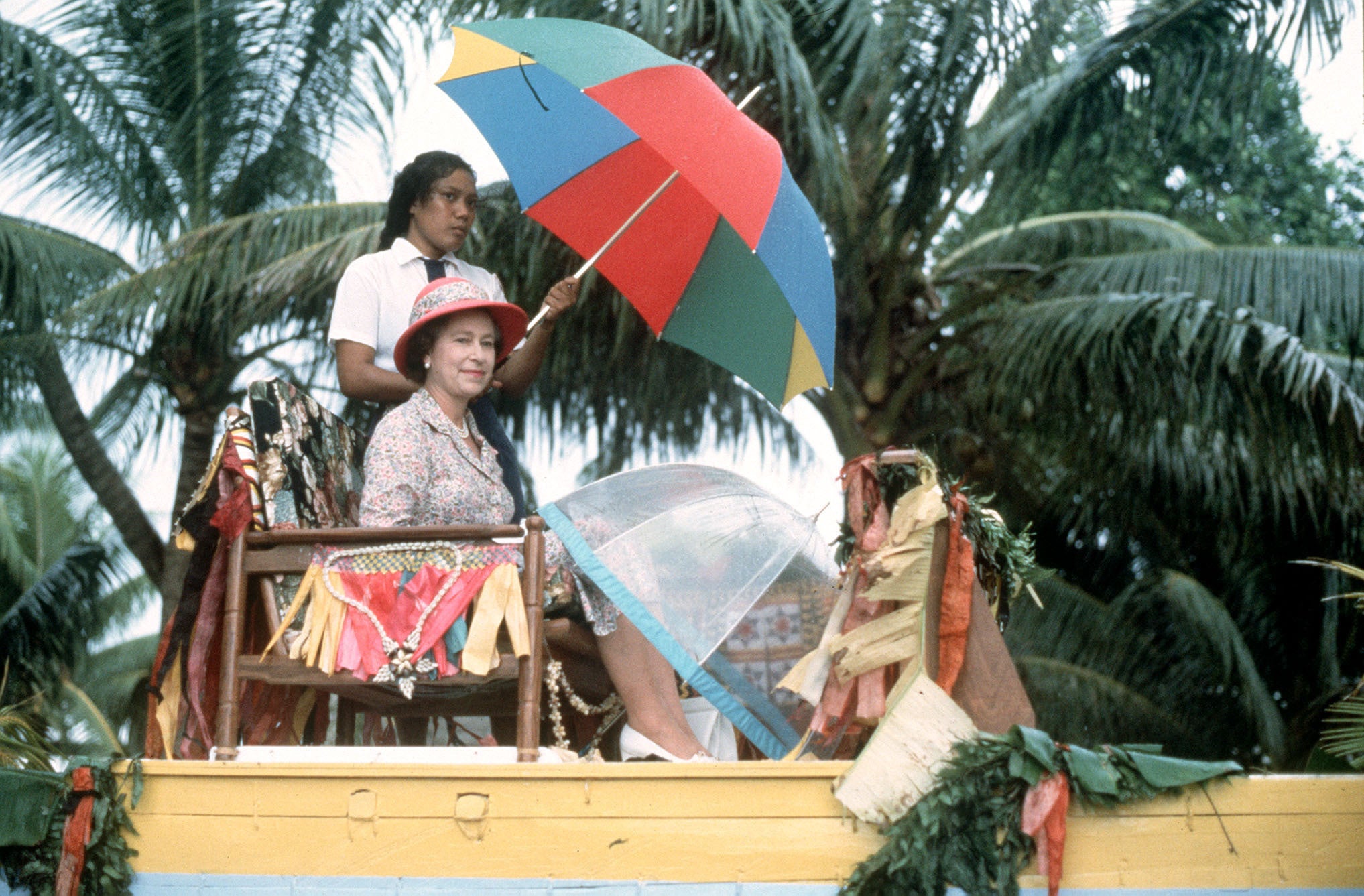 The Queen is carried shoulder high in a canoe to the shore of Tuvalu at the end of her visit to the South Sea Islands in 1982 (PA)