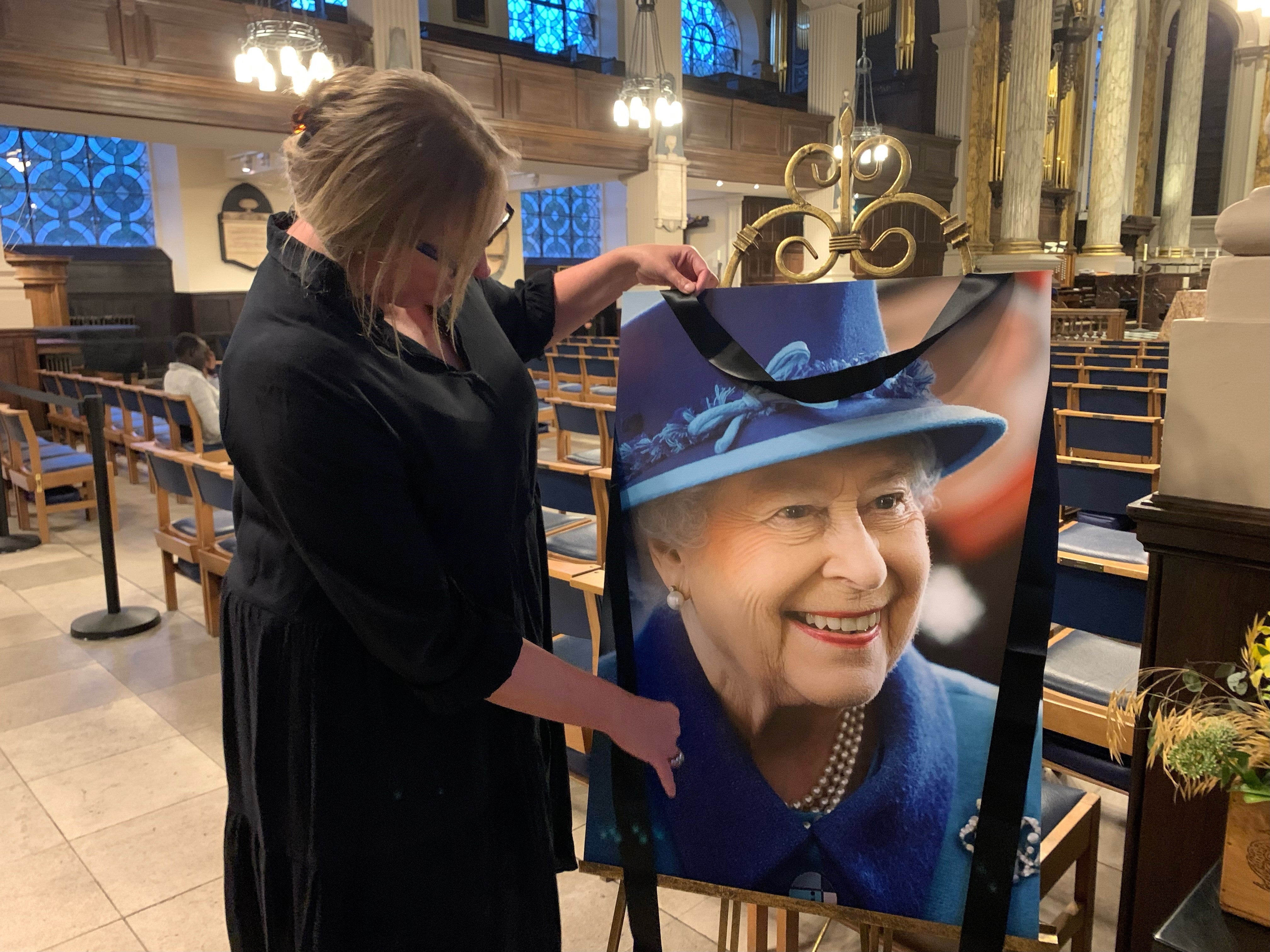 Anna Pitt, chief executive of Birmingham’s St Philip’s Cathedral puts out a picture of the Queen. Mourners have been invited to reflect, say prayers and light a candle (Richard Vernalls/PA)