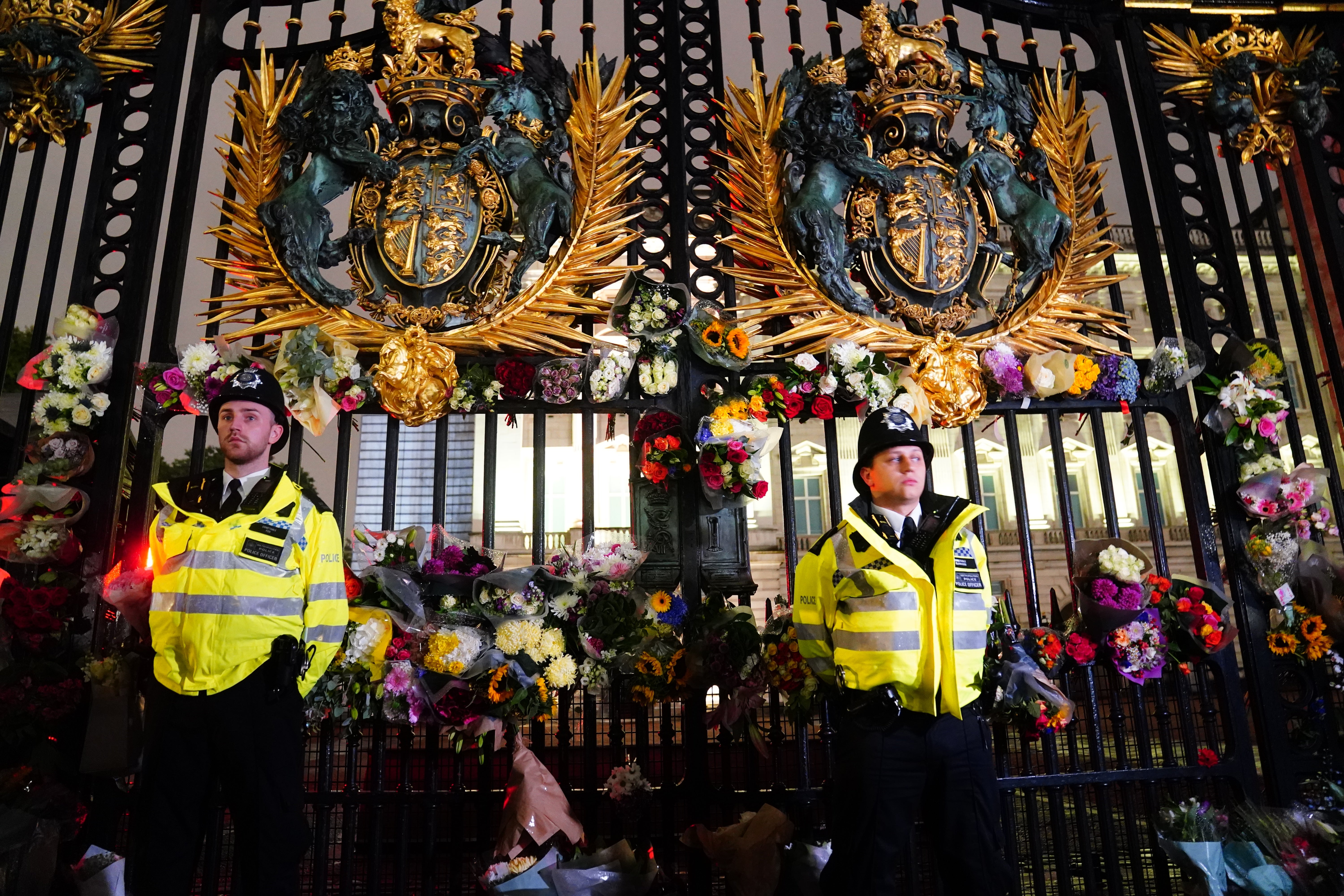 Police officers stand amongst floral tributes left outside Buckingham Palace