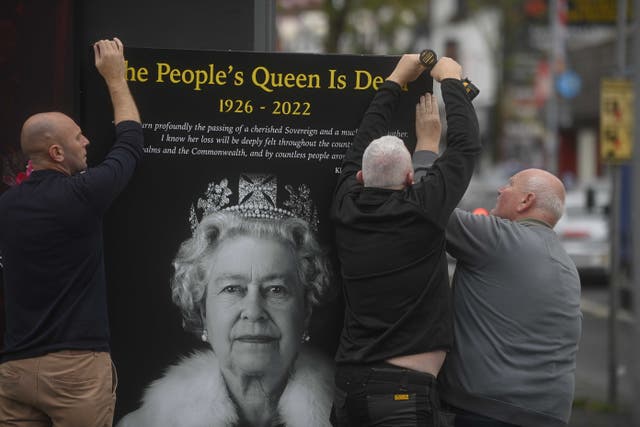 Council workers and local community representatives hang a mural on a wall on Crimea street off the Shankill road in Belfast following the death of the Queen (Mark Marlow/PA)