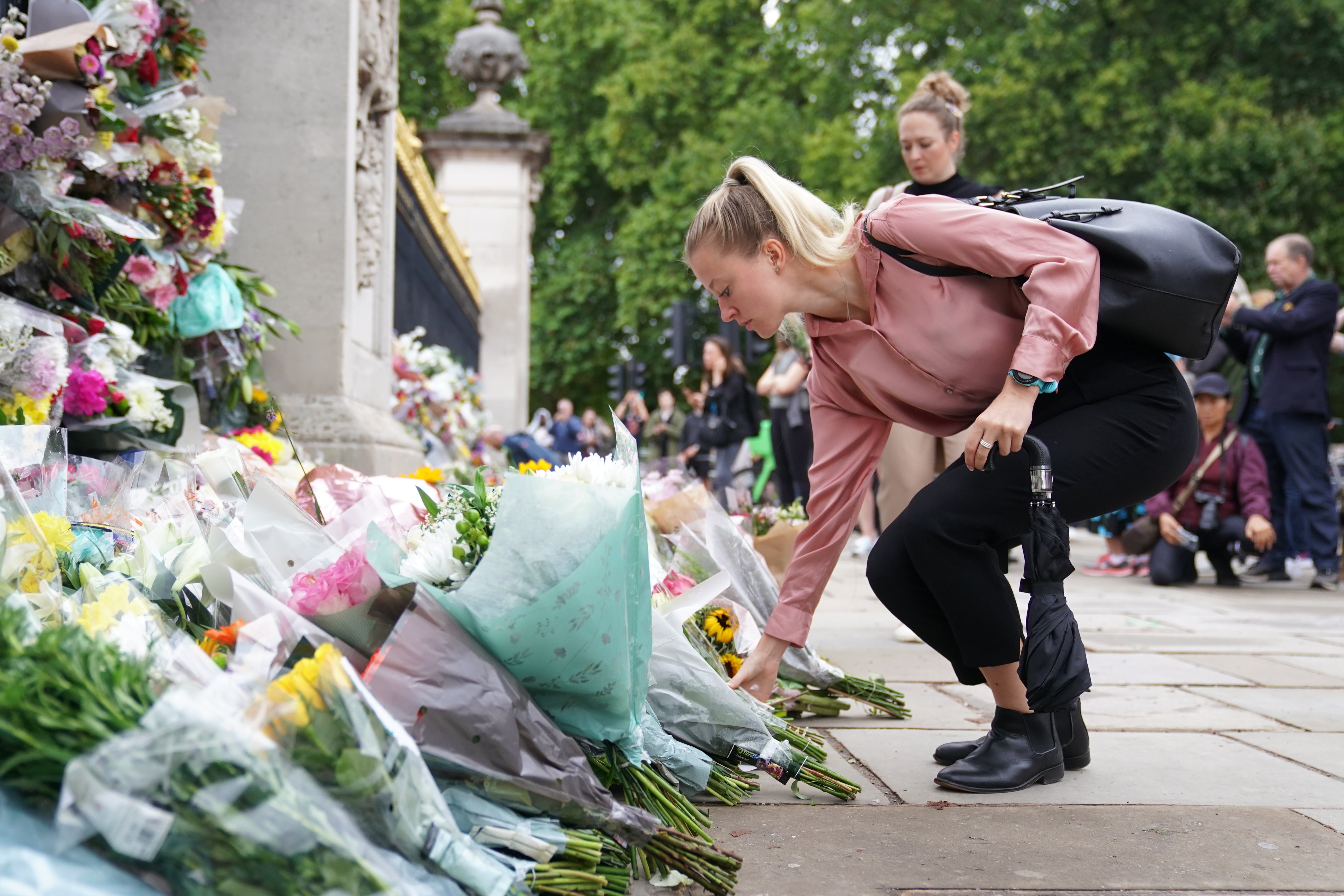 A woman lays flowers outside Buckingham Palace (Kirsty O’Connor/PA)