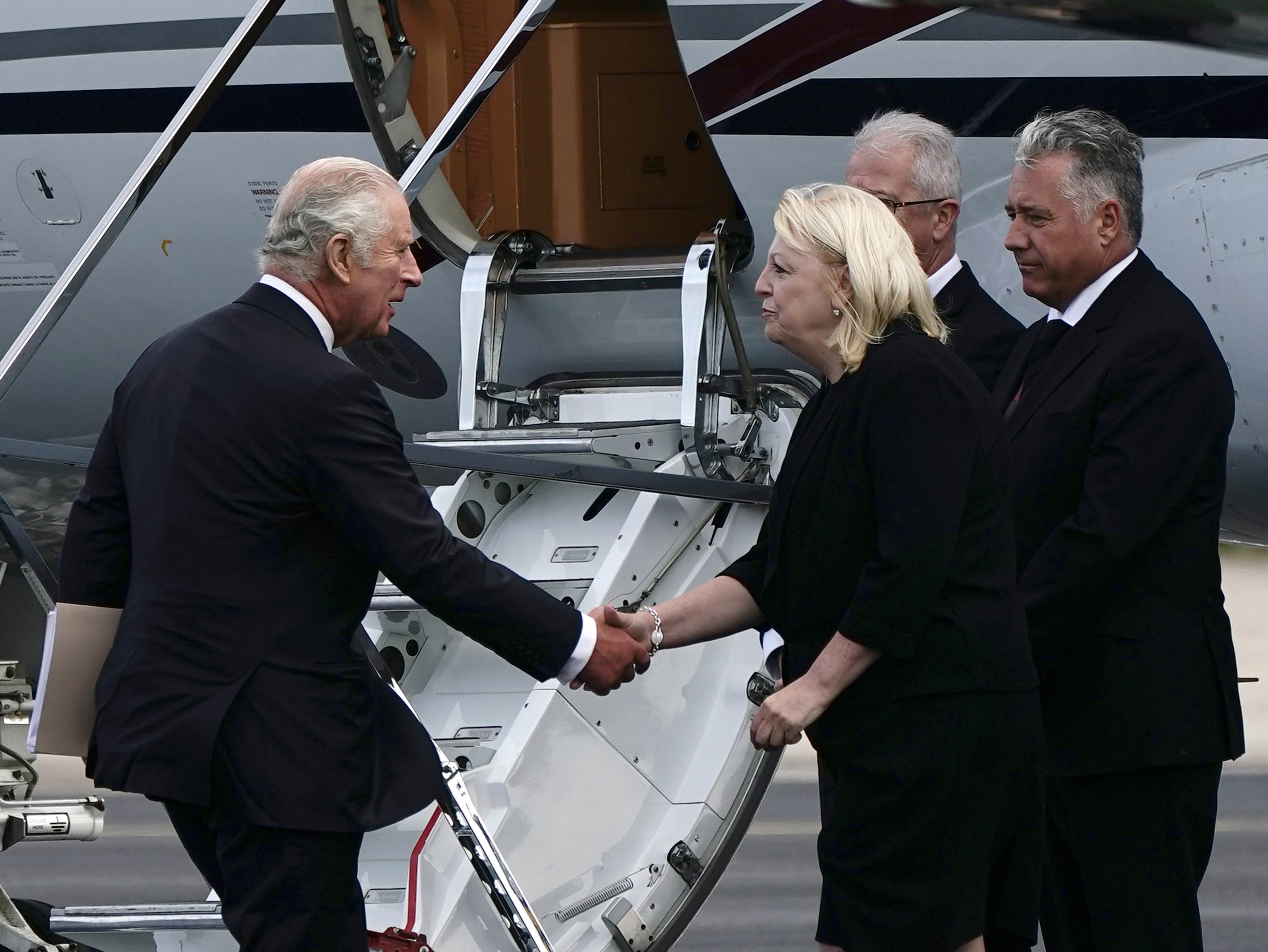 King Charles III stopped to shake hands and speak with three people waiting beside a plane before climbing on board