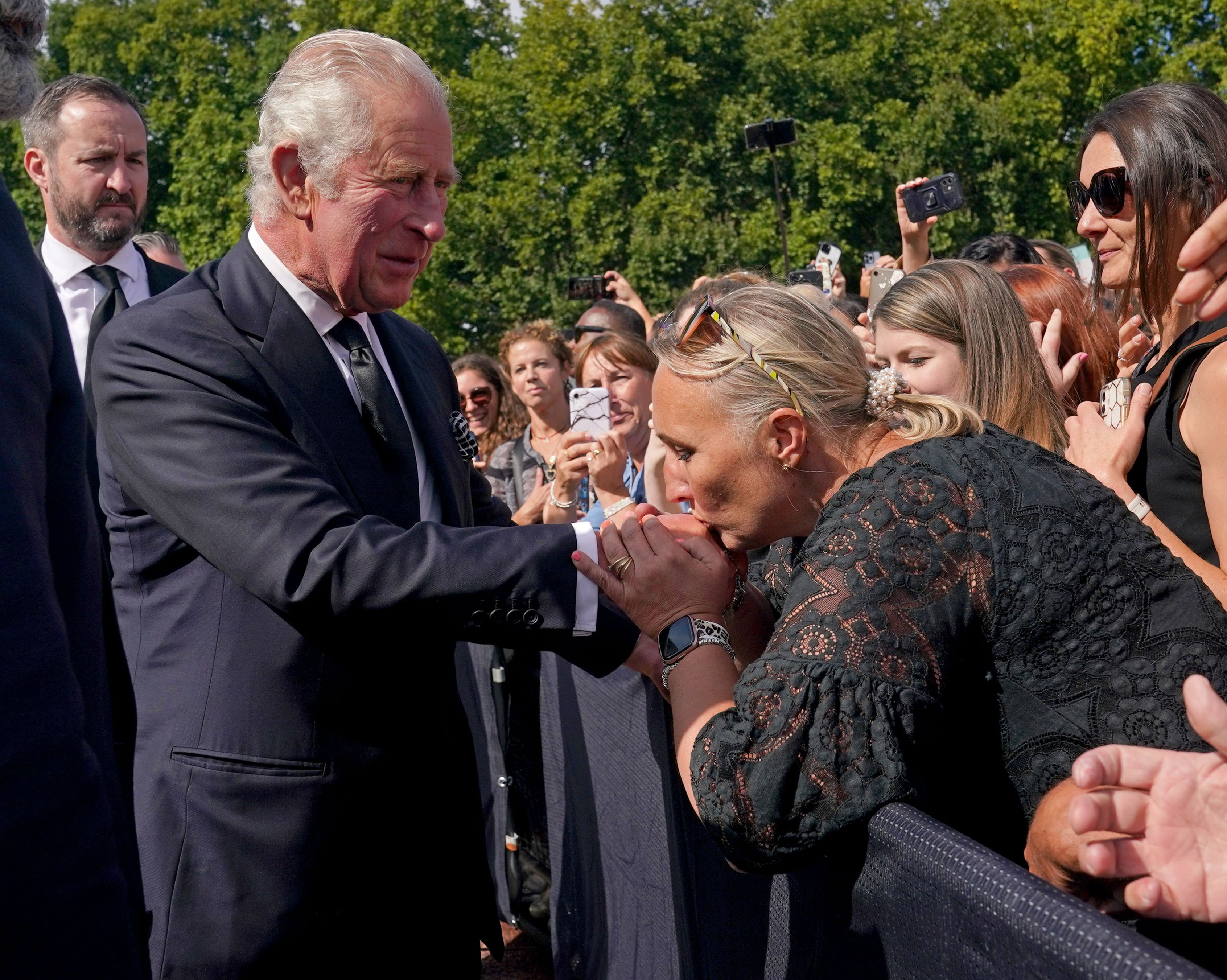 A well-wisher kisses the hand of King Charles III
