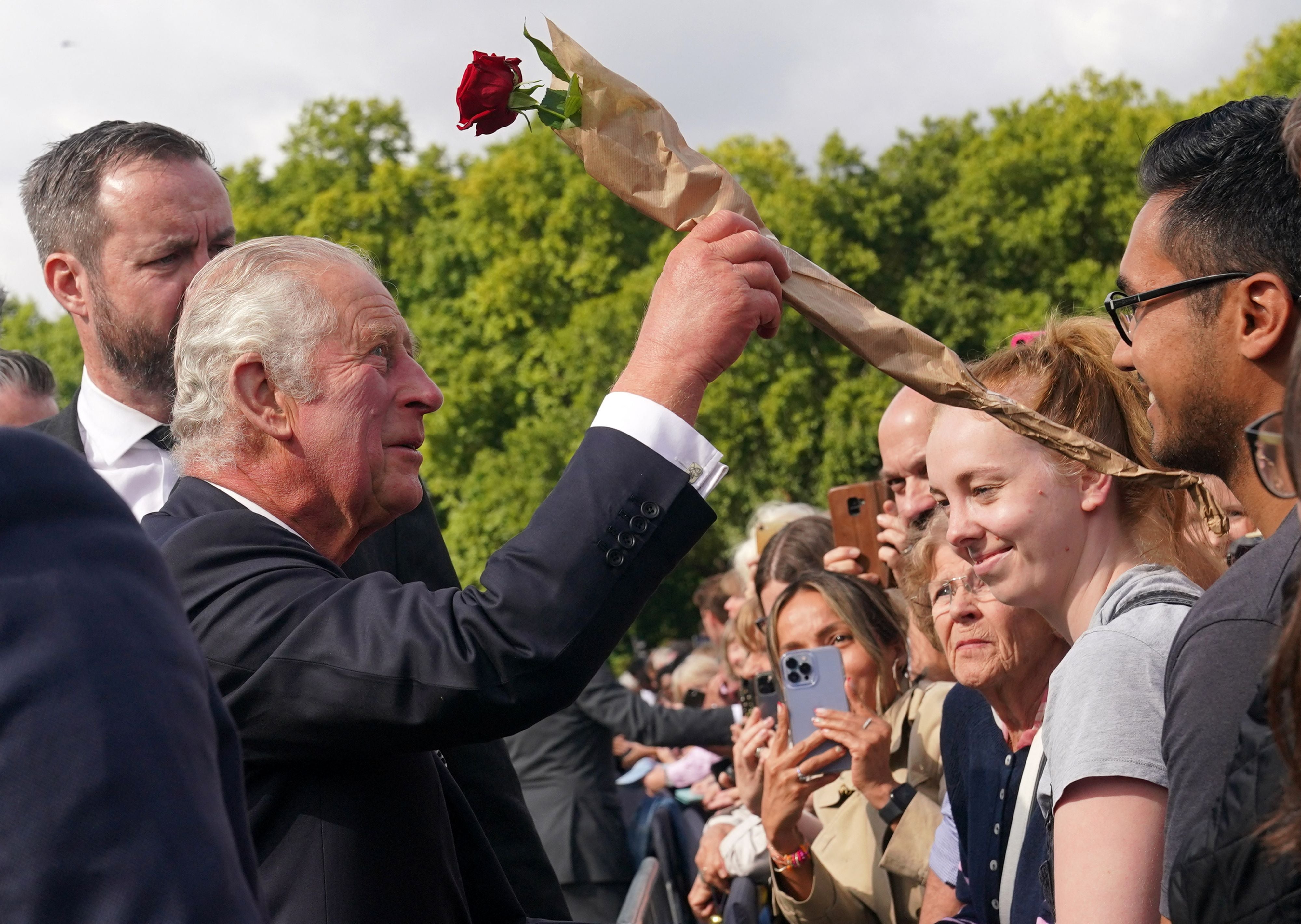 King Charles III accepts a single rose from a member of the public