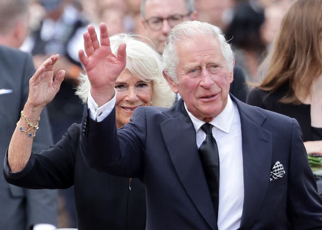 <p>King Charles III and Camilla, Queen Consort wave after viewing floral tributes to the late Queen Elizabeth II outside Buckingham Palace</p>