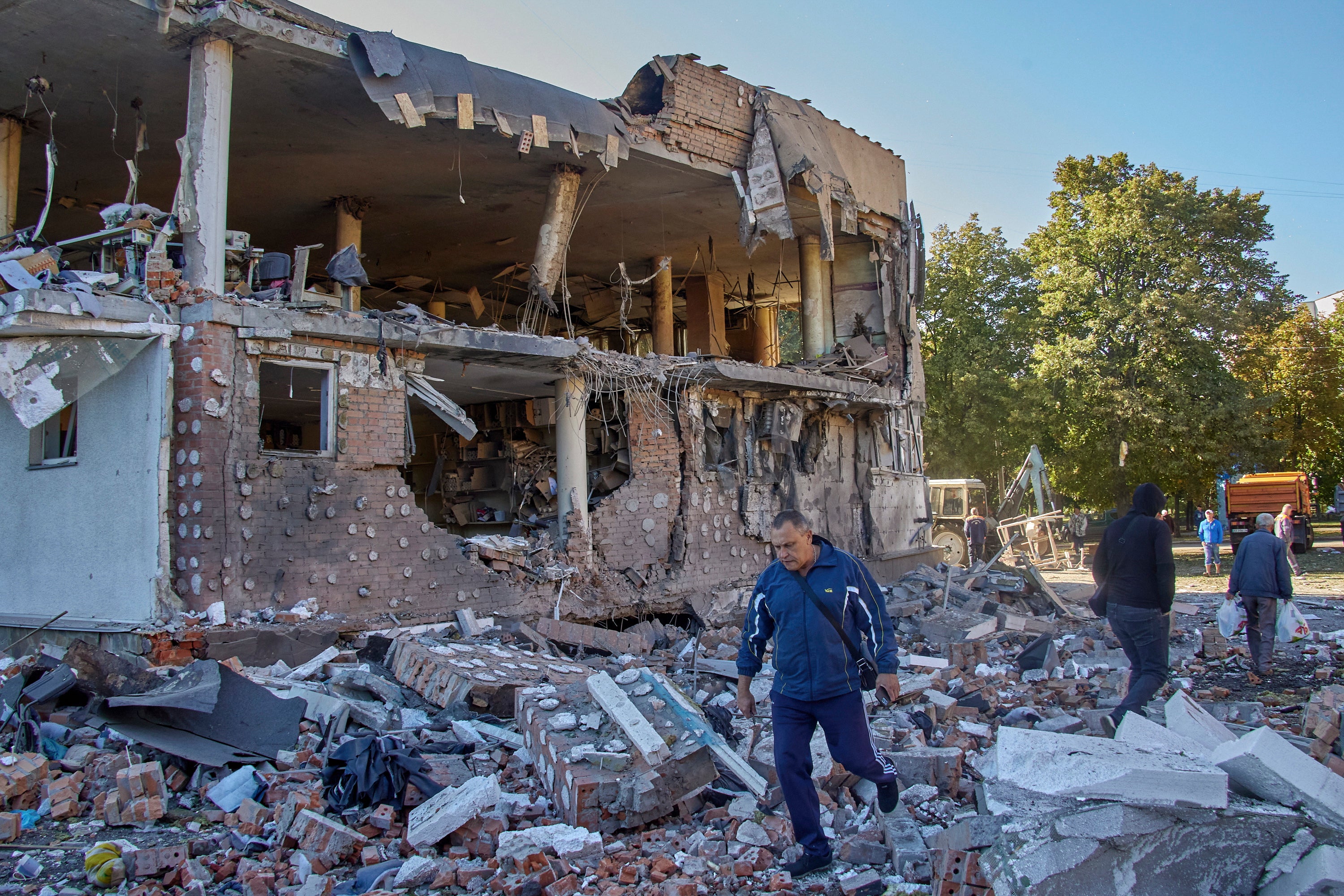 Locals walk past an administrative building destroyed in a rocket attack in Kharkiv