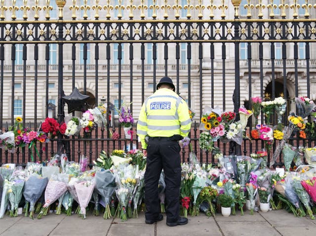 Un oficial de policía mira las flores colocadas frente al Palacio de Buckingham, Londres, tras la muerte de la reina Isabel II el jueves.