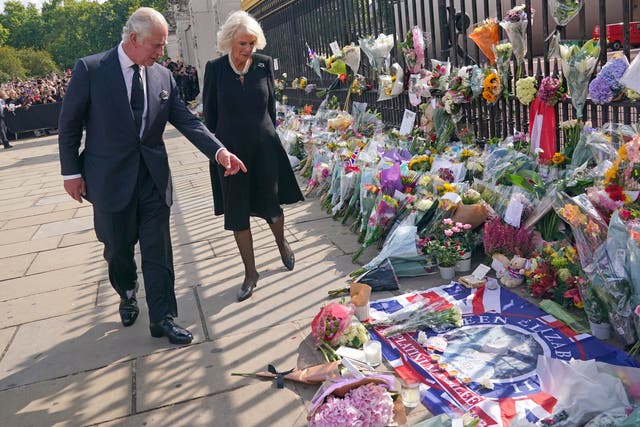 The King and Queen view tributes left outside Buckingham Palace (Yui Mok/PA)