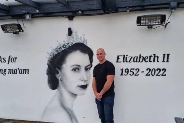 Scott Wilcock stood next to his mural to the Queen at the Queens Arms pub in Manchester (Scott Wilcock/PA)