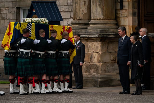 Vice Admiral Timothy Laurence and the Princess Royal stand solemnly as the coffin of Queen Elizabeth II, draped with the Royal Standard of Scotland, completes its journey from Balmoral to the Palace of Holyroodhouse in Edinburgh (PA)