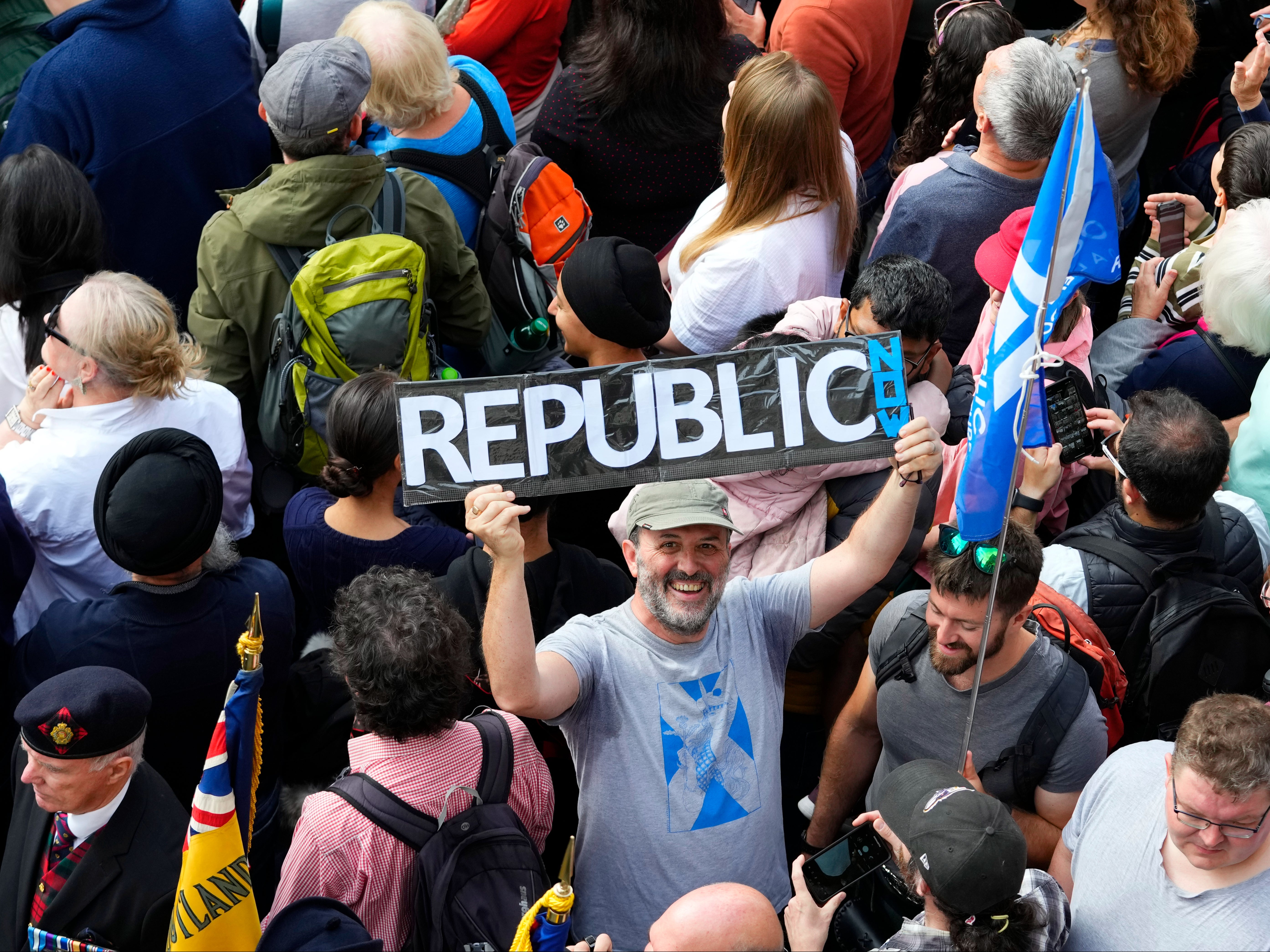 A man holds up a sign among members of the public attending a public Proclamation to announce the Accession of King Charles III, outside St Giles Cathedral, on the Royal Mile, in Edinburgh, Scotland, Sunday, Sept. 11, 2022