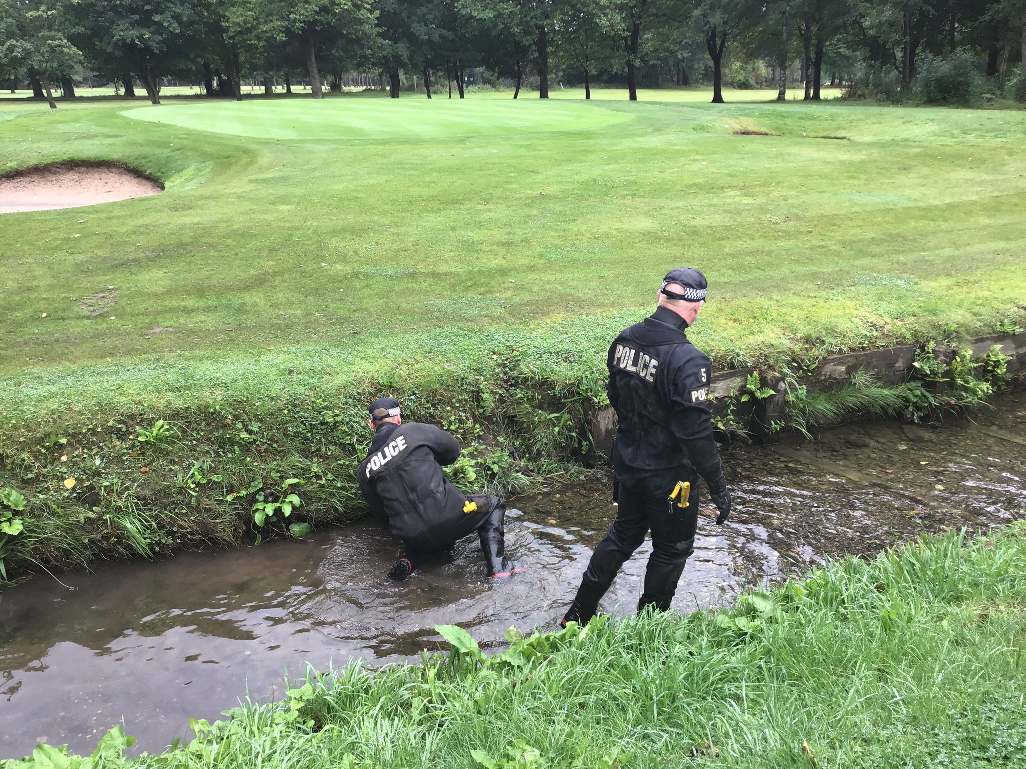 Officers search waterways at a golf course for the murder weapon
