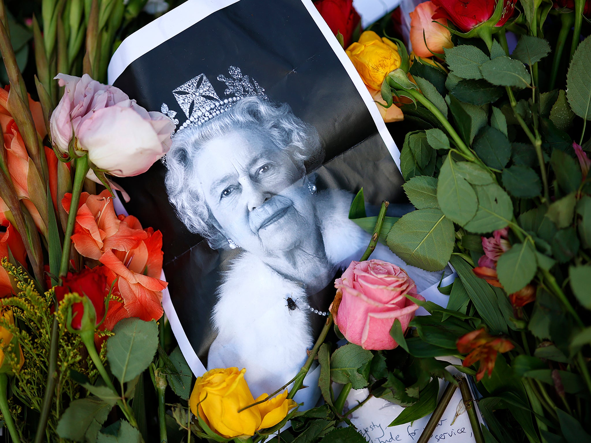 A photograph of Queen Elizabeth II lays among flowers left at a memorial site near Buckingham Palace this weekend