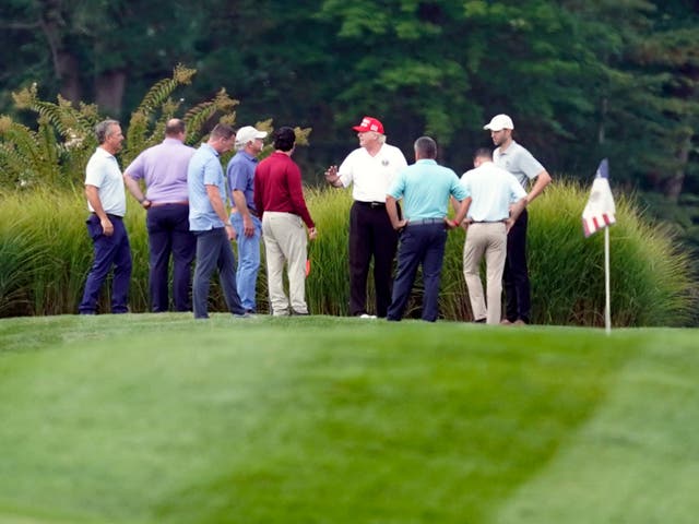 El expresidente Donald Trump, centro, en su campo de golf con otros en el Trump National Golf Club en Sterling, Virginia, el lunes 12 de septiembre de 2022