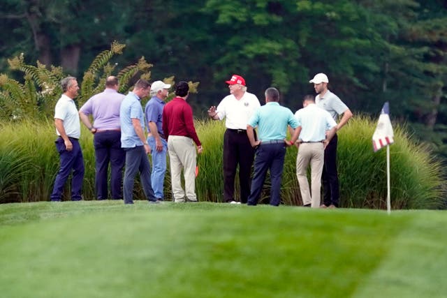 El expresidente Donald Trump, centro, en su campo de golf con otros en el Trump National Golf Club en Sterling, Virginia, el lunes 12 de septiembre de 2022