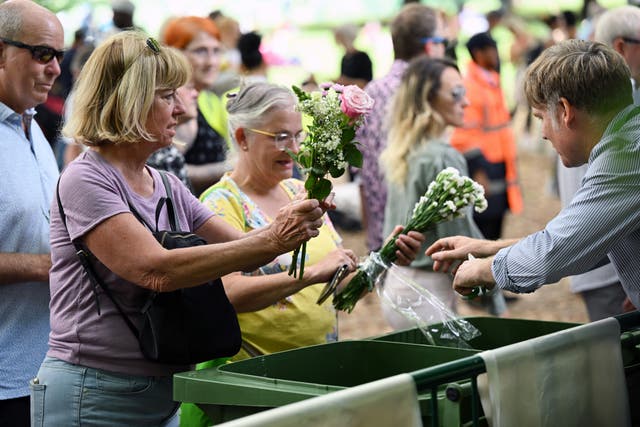 <p>Volunteers remove the plastic from floral tributes to allow the flowers to be composted and the plastic recycled at Green Park on 12 September.</p>