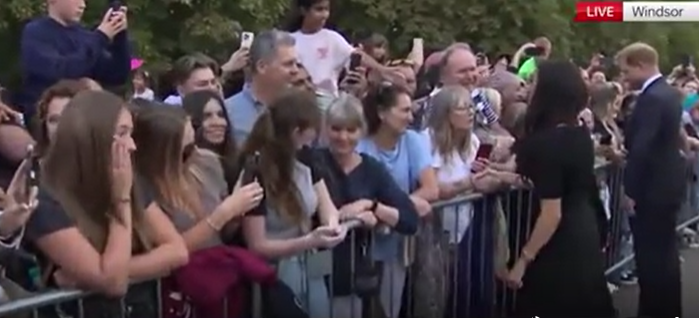 Footage shows one woman looking down as Meghan smiles at her