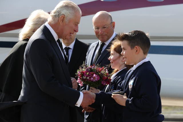 King Charles III and the Queen Consort are greeted by 10-year-olds Ella Smith and Lucas Watt as they arrive at Belfast City Airport (Liam McBurney/PA)
