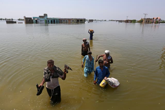 Victims of flooding from monsoon rains carry belongings salvaged from their flooded home in the Dadu district of Sindh Province, Pakistan (Fareed Khan/AP)
