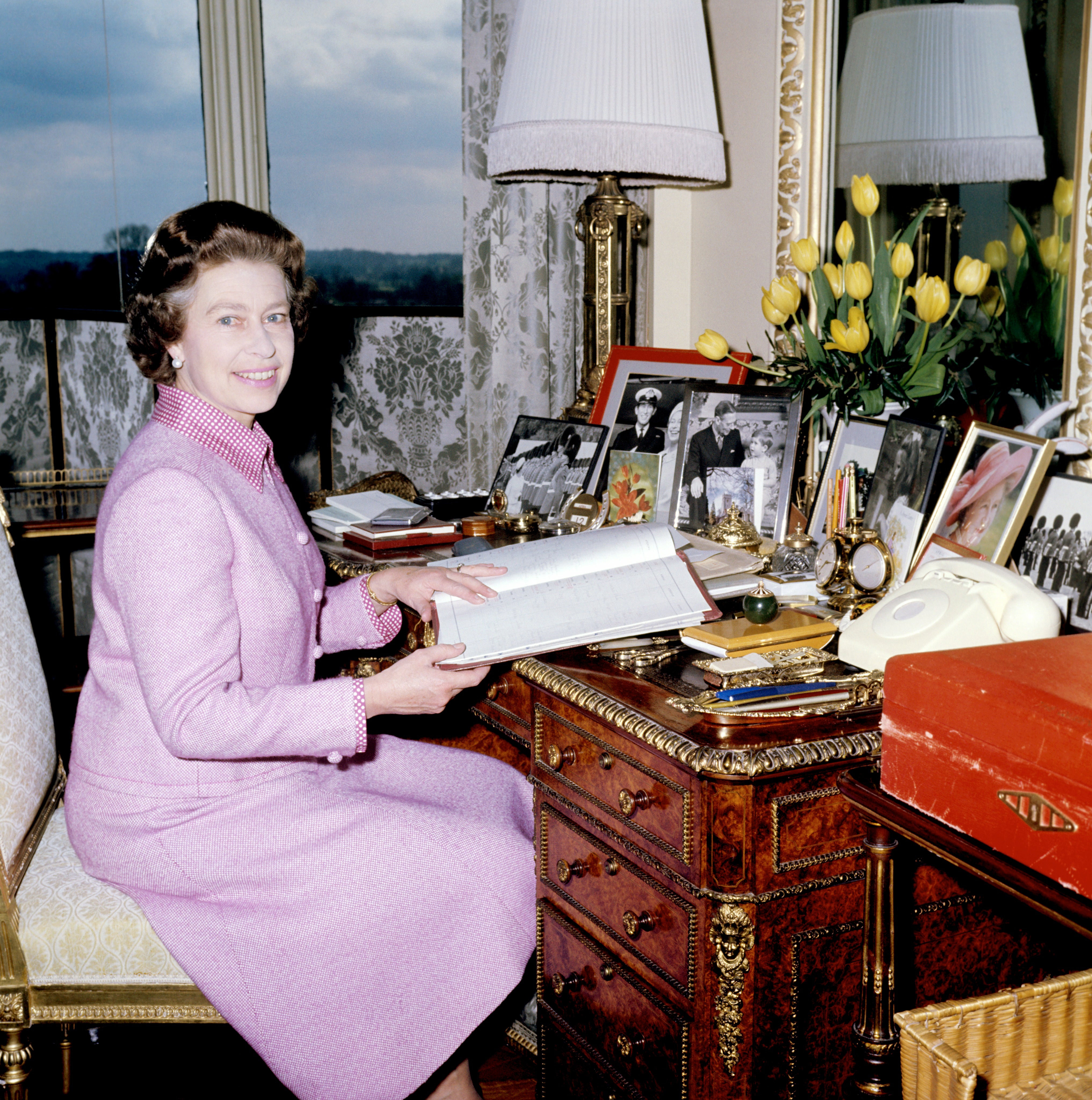 Queen Elizabeth in her sitting room at Windsor Castle looking through her diary of engagements, with a famous red box by her side (PA)
