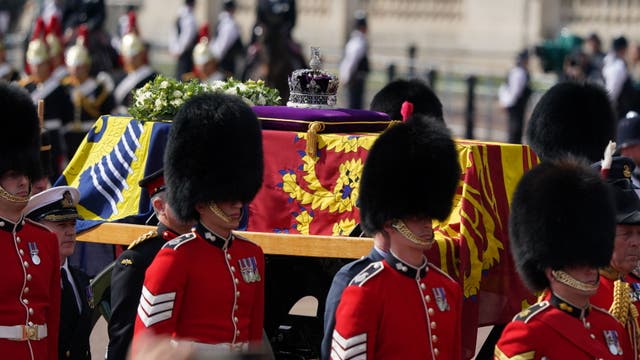 The coffin of the Queen draped in the Royal Standard with the Imperial State Crown placed on top, is carried on a horse-drawn gun carriage from Buckingham Palace (Ian West/PA)
