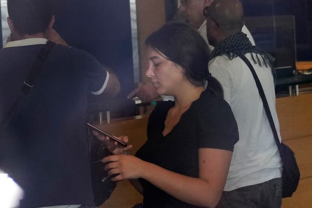 <p>Lebanese Sali Hafez, centre, looks at her phone after breaking into a Blom Bank branch brandishing what she later said was a toy pistol </p>