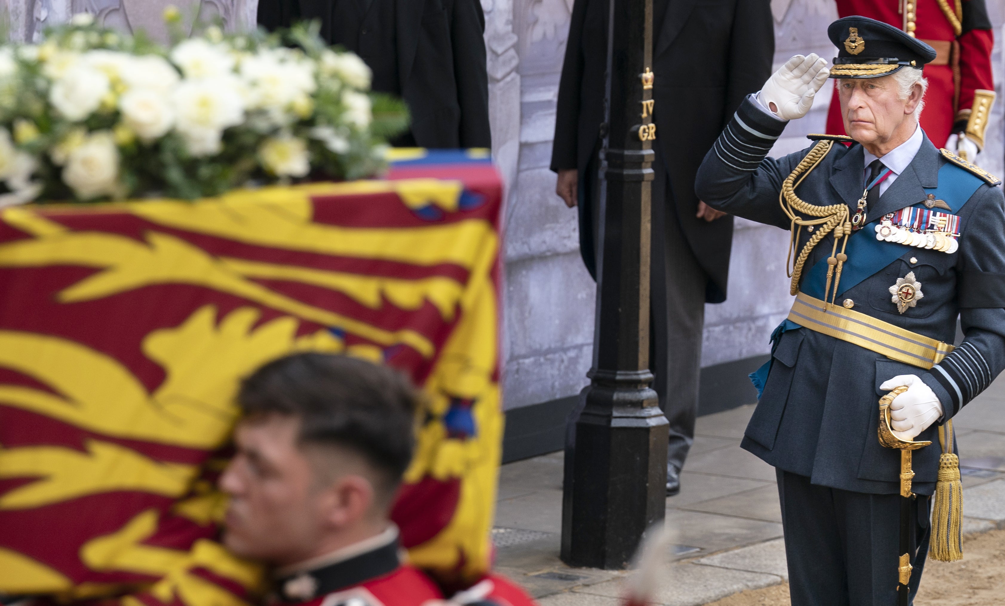 King Charles III salutes as the bearer party carry the coffin of his mother into Westminster Hall (Danny Lawson/PA)