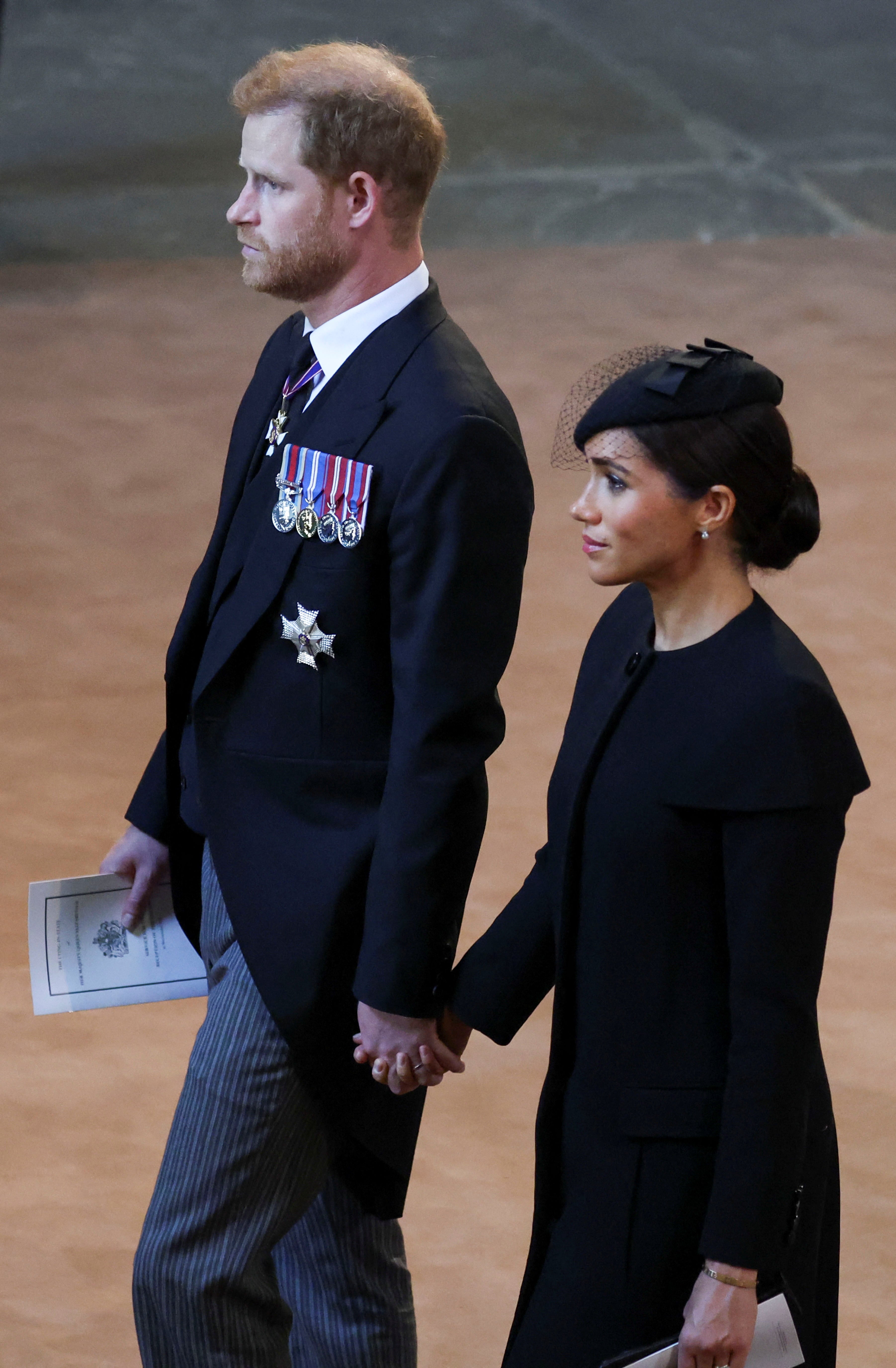 Prince Harry and Meghan Markle hold hands as they exit Westminster Hall service