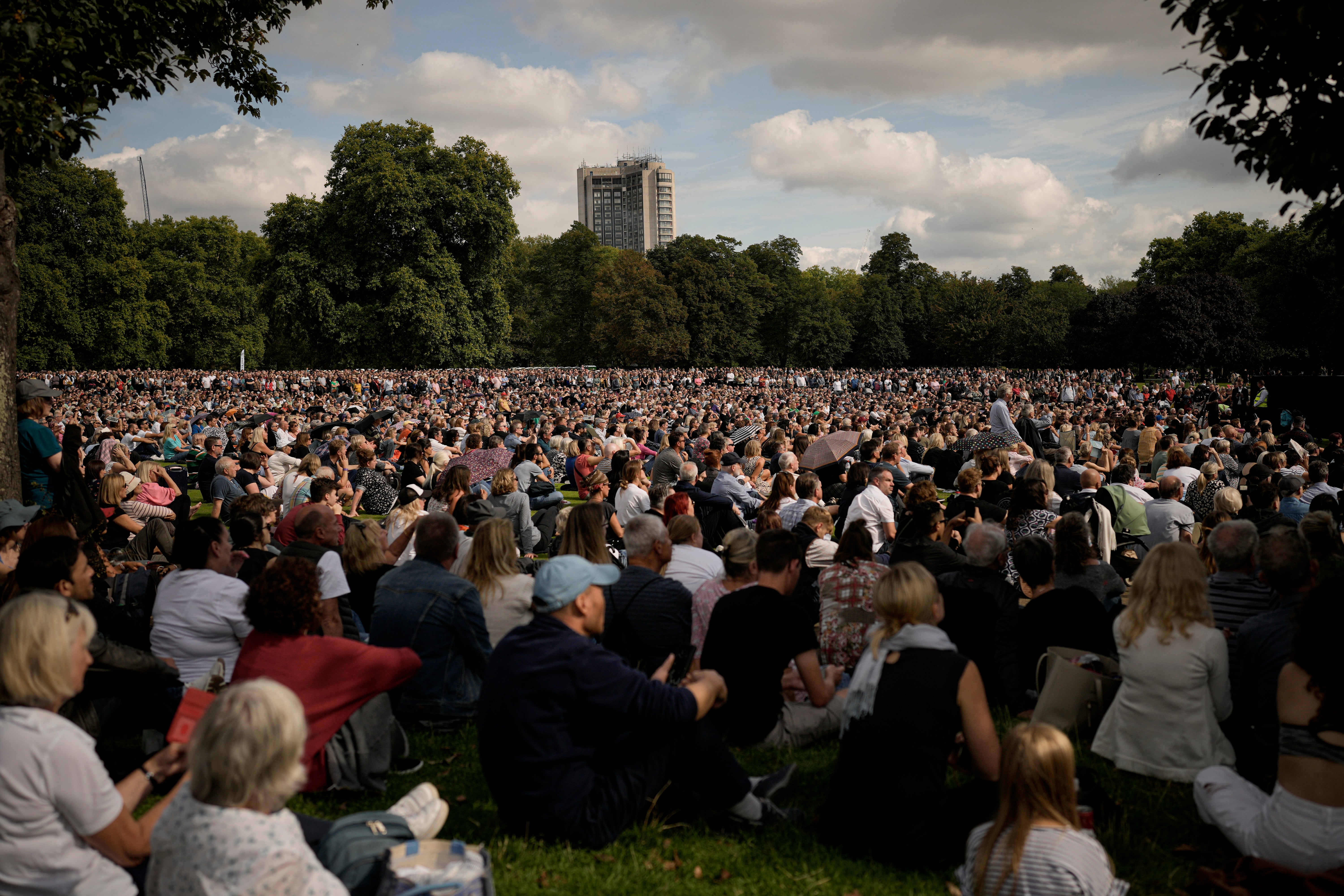 People sitting in Hyde Park, London, watch screens broadcasting the procession of the coffin of Queen Elizabeth II