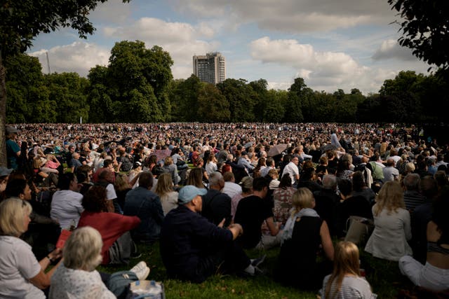 <p>People sitting in Hyde Park, London, watch screens broadcasting the procession of the coffin of Queen Elizabeth II</p>