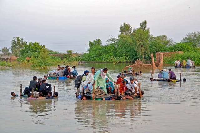<p>Internally displaced people wade through the floodwaters in Pakistan’s historic floods</p>